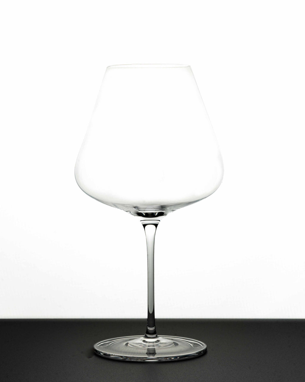 "The Mistress" red Wine Glass in white background and black - Luxury, premium and silent excellence design for wine lovers. It has tapered big bowl for aromatic wine experience. The glass is empty and shows its profile!